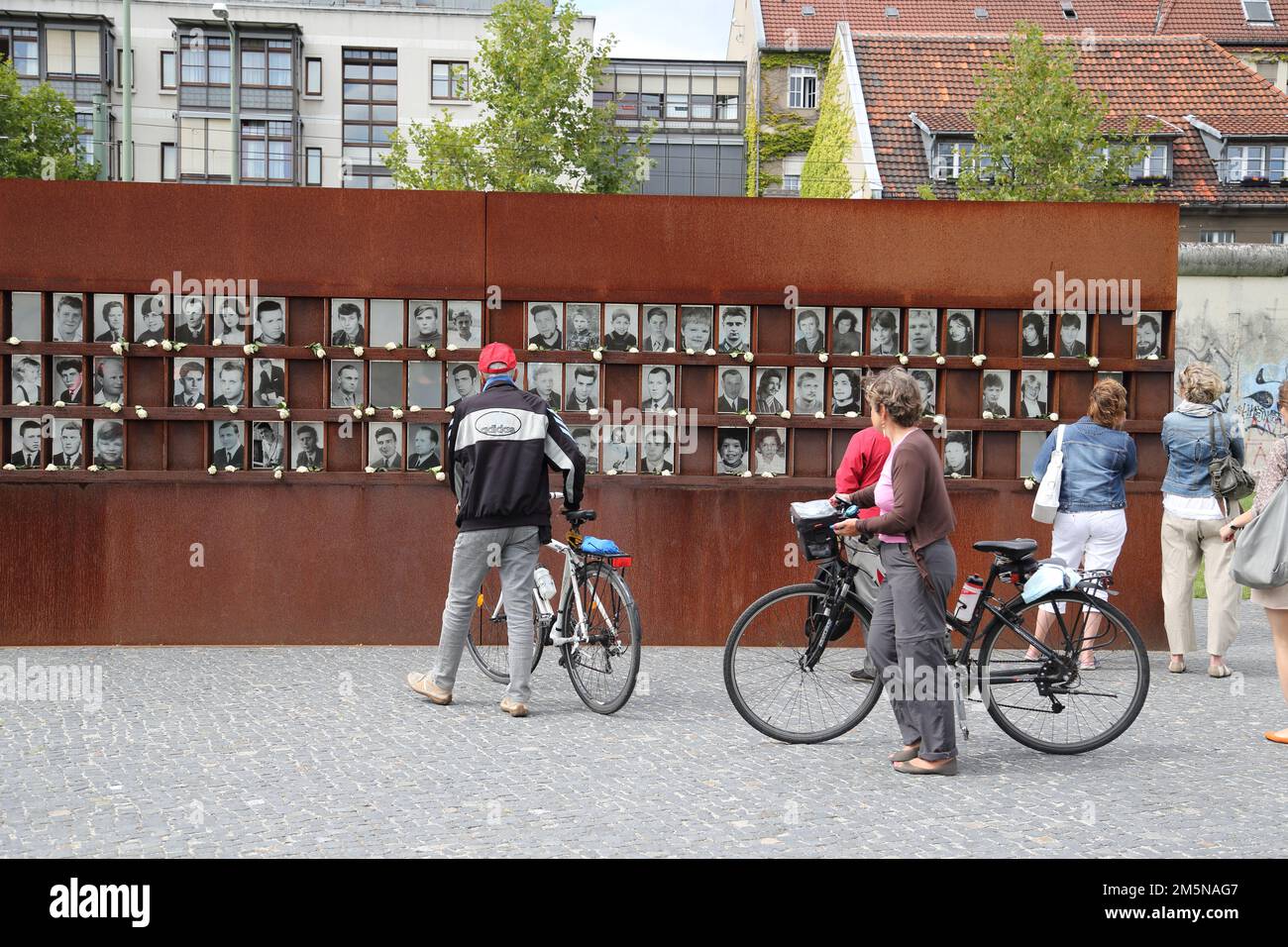 I turisti studiano le foto delle vittime che sono morte cercando di fuggire dalla Germania orientale al Gedenkstätte Berliner Mauer o al Memoriale del Muro di Berlino a Berlino, Germania Foto Stock