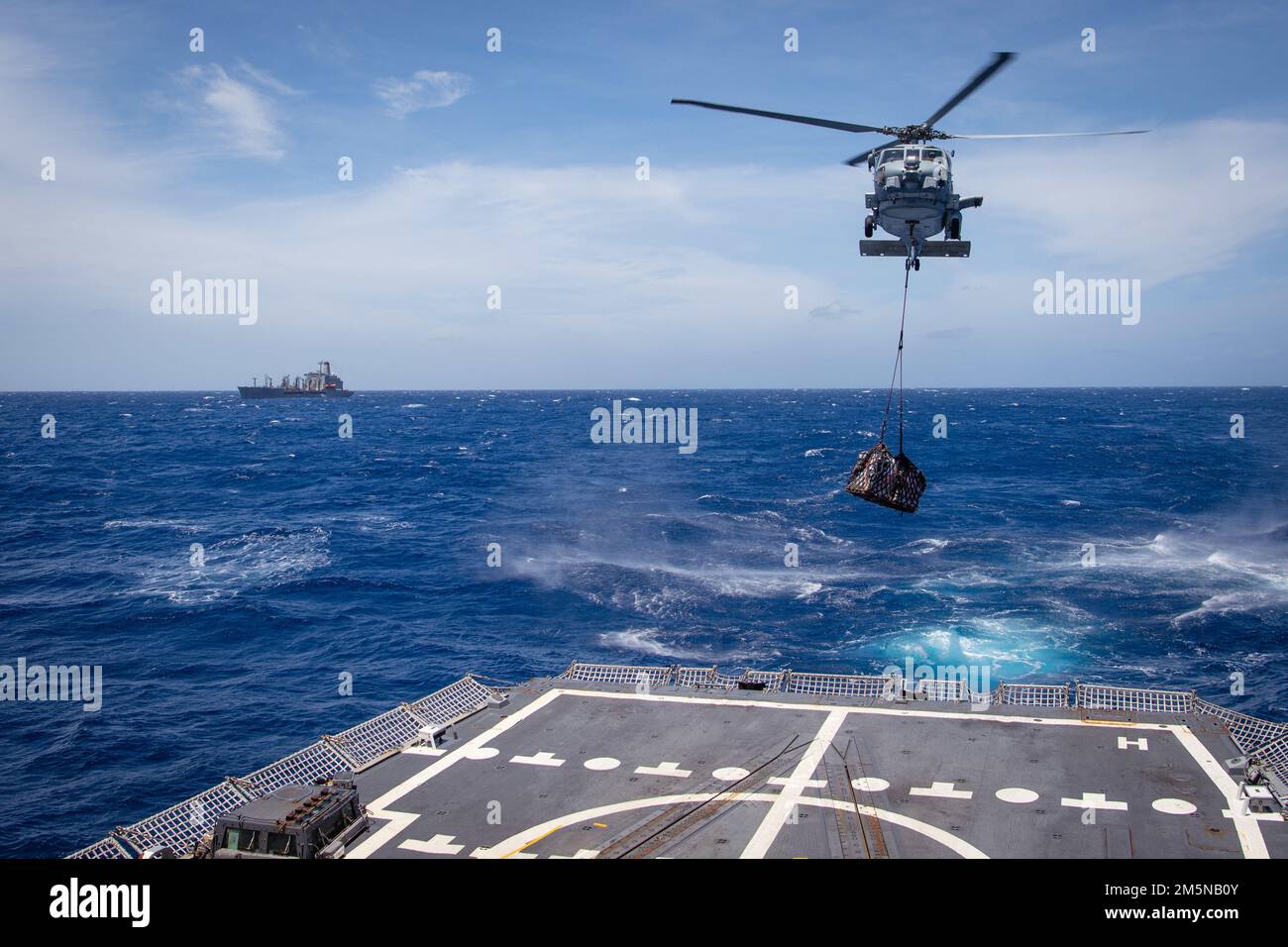 220330-N-TT059-2083 SOUTH CHINA SEA (30 marzo 2022) Un elicottero MH-60R Sea Hawk dei 'Magici' di Helicopter Maritime Strike Squadron (HSM) 35 trasporta durante le operazioni di rifornimento verticale (VERTREP) con USNS Guadalupe (T-AO 200) a bordo del cacciatorpediniere missilistico guidato USS Momsen (DDG 92). Momsen è assegnato al Comandante, Task Force 71/Destroyer Squadron (DESRON) 15, la più grande desolata della Marina e la principale forza di combattimento della flotta degli Stati Uniti 7th, ed è in corso il supporto di un libero e aperto Indo-Pacifico. Foto Stock