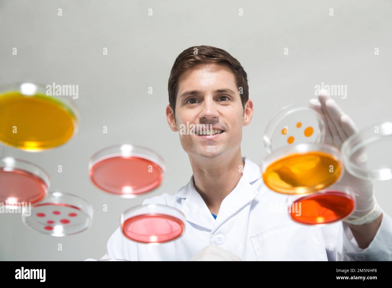 Uomini stranieri con capsule di Petri nell'esperimento di laboratorio Foto Stock