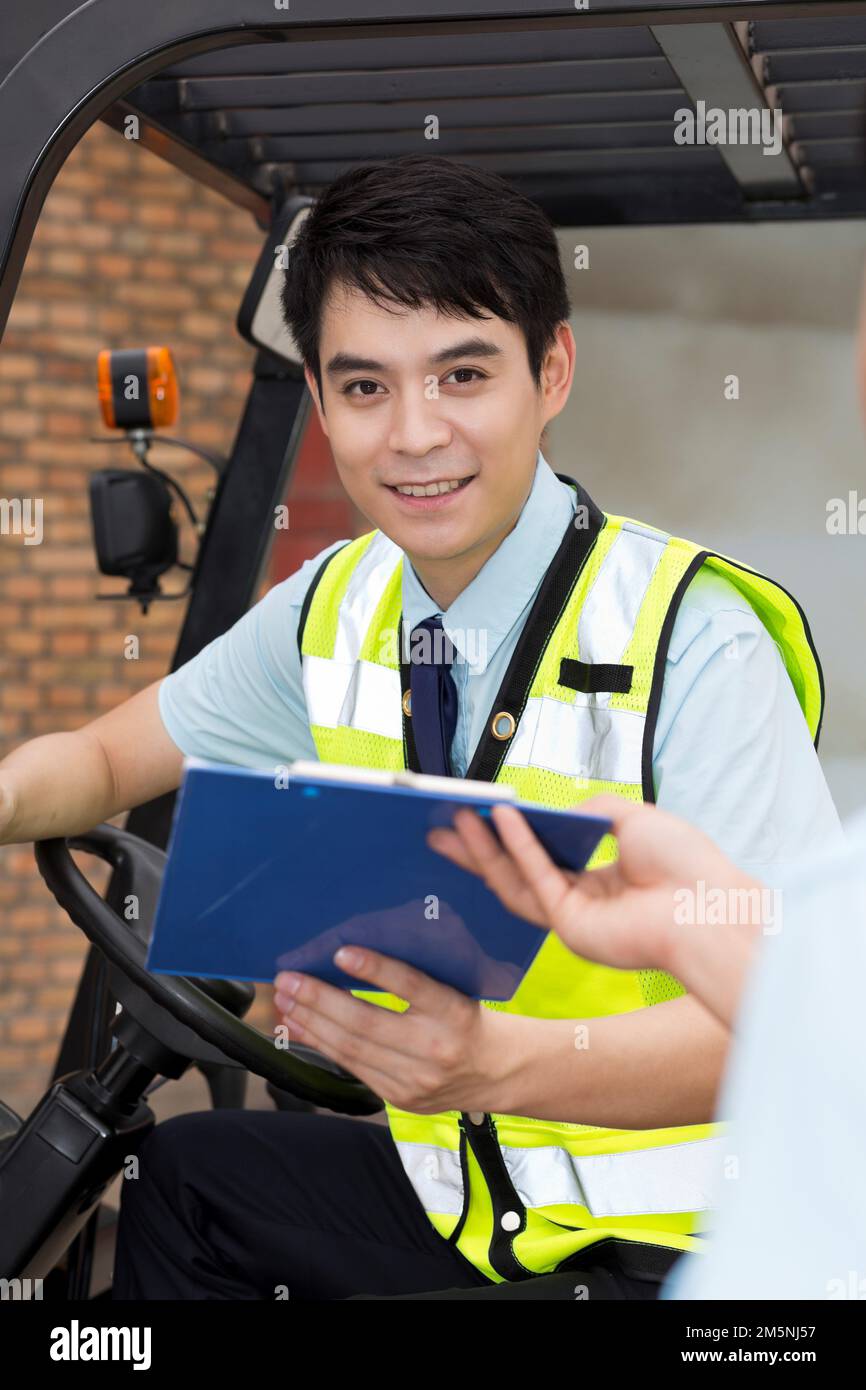 Il personale addetto alla gestione del magazzino logistico parla per guidare un carrello elevatore a forche Foto Stock