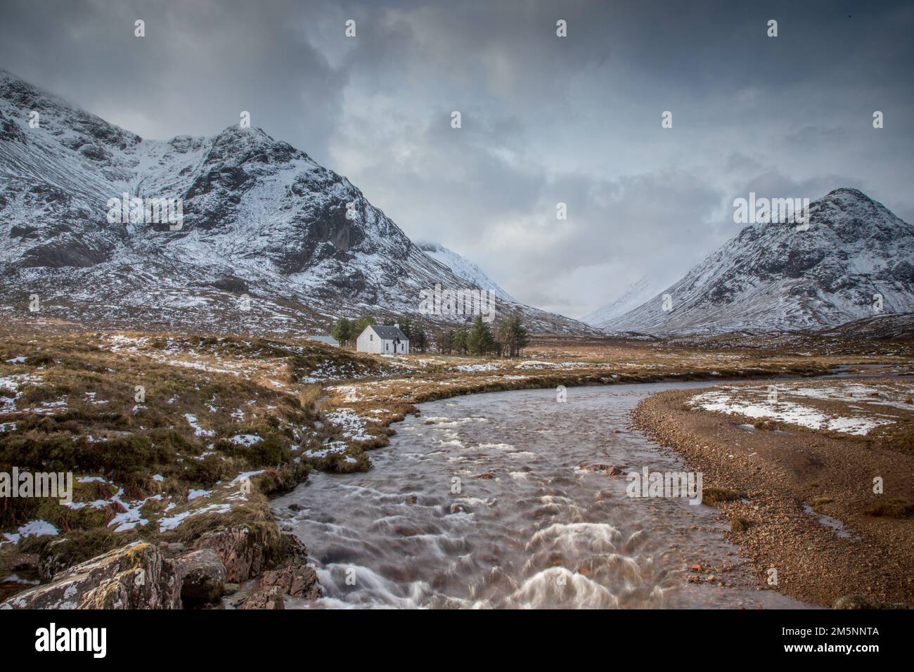 Old Cottage nelle Highlands scozzesi vicino a Glencoe in una giornata d'inverno con neve e montagne della Scozia Foto Stock