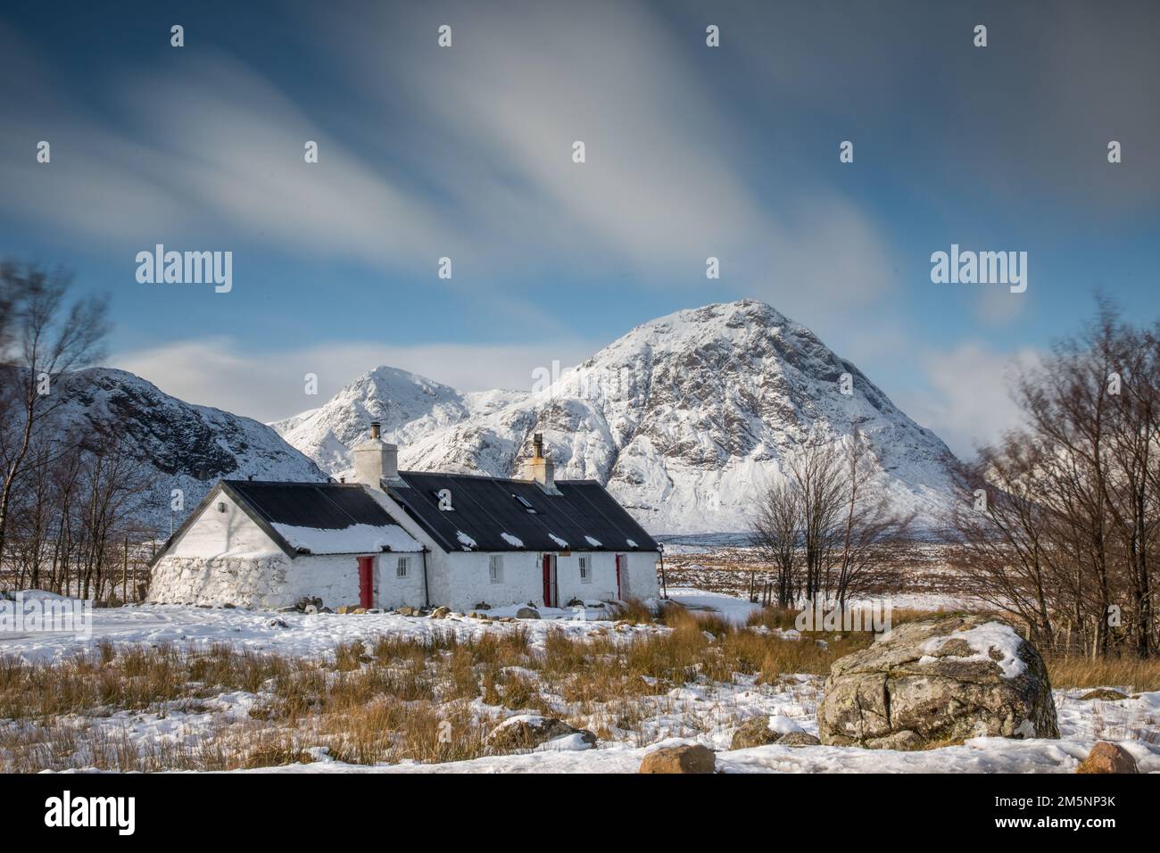 Old Cottage nelle Highlands scozzesi vicino a Glencoe in una giornata d'inverno con neve e montagne della Scozia Foto Stock