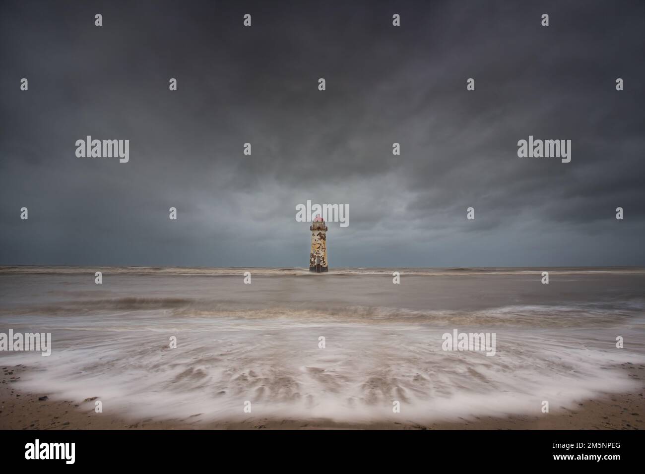 Il tempo attanagliato Faro in un paesaggio fotografato circondato da mare e acqua. in un giorno tempestoso Foto Stock