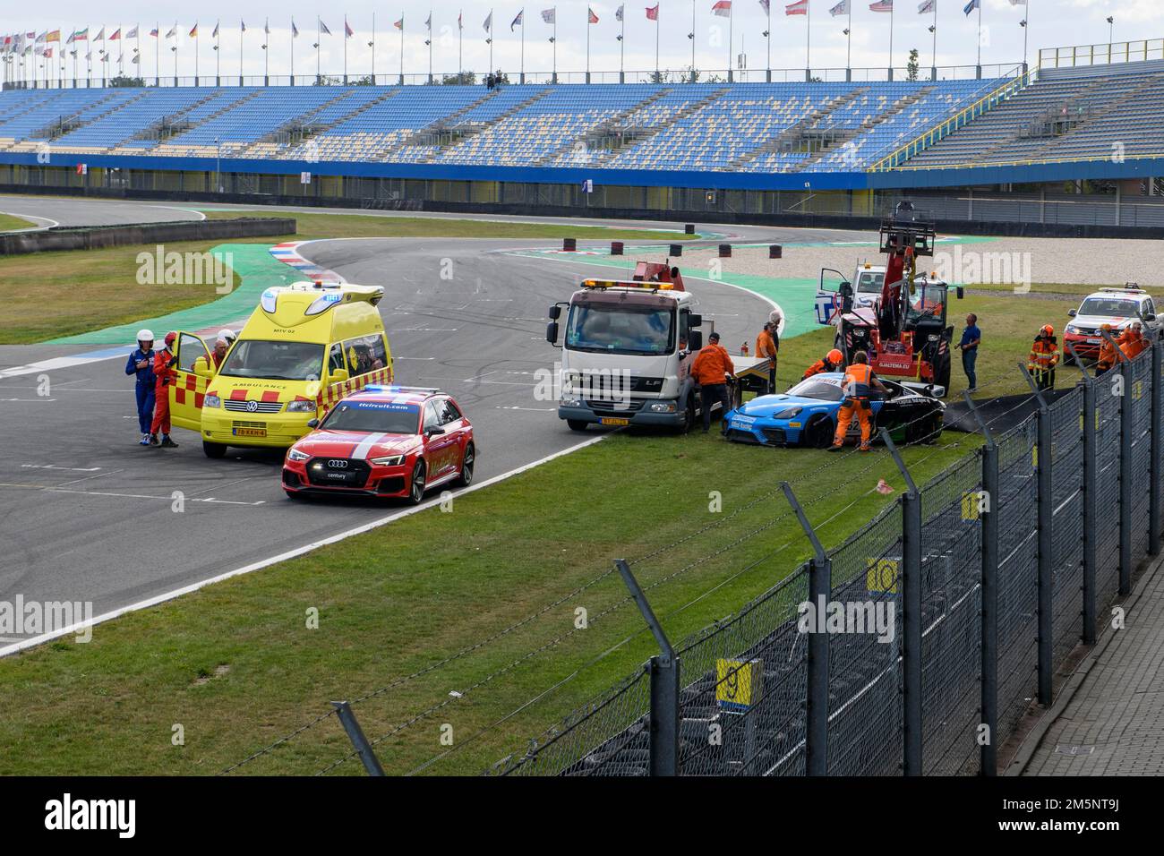 Vista della scena dopo un grave incidente da corsa, ha lasciato l'ambulanza gialla, davanti all'auto medica rossa da un evento da corsa, accanto ad essa il camion di traino e. Foto Stock
