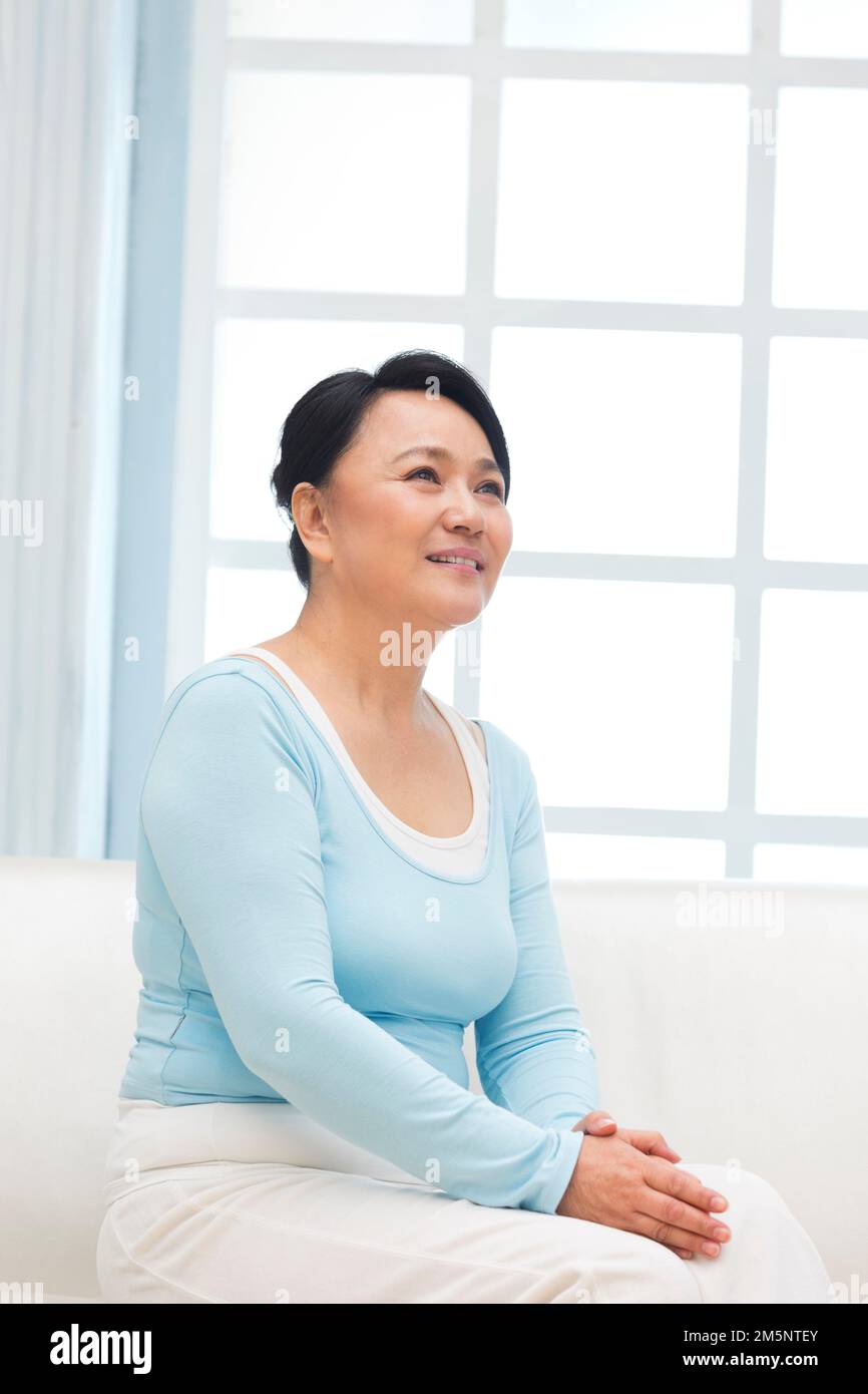 La donna seduta sul divano Foto Stock