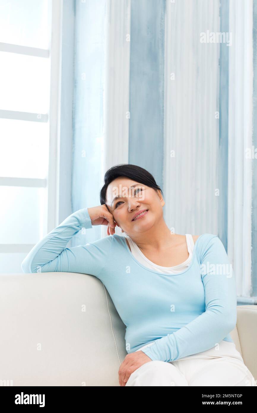 La donna seduta sul divano Foto Stock