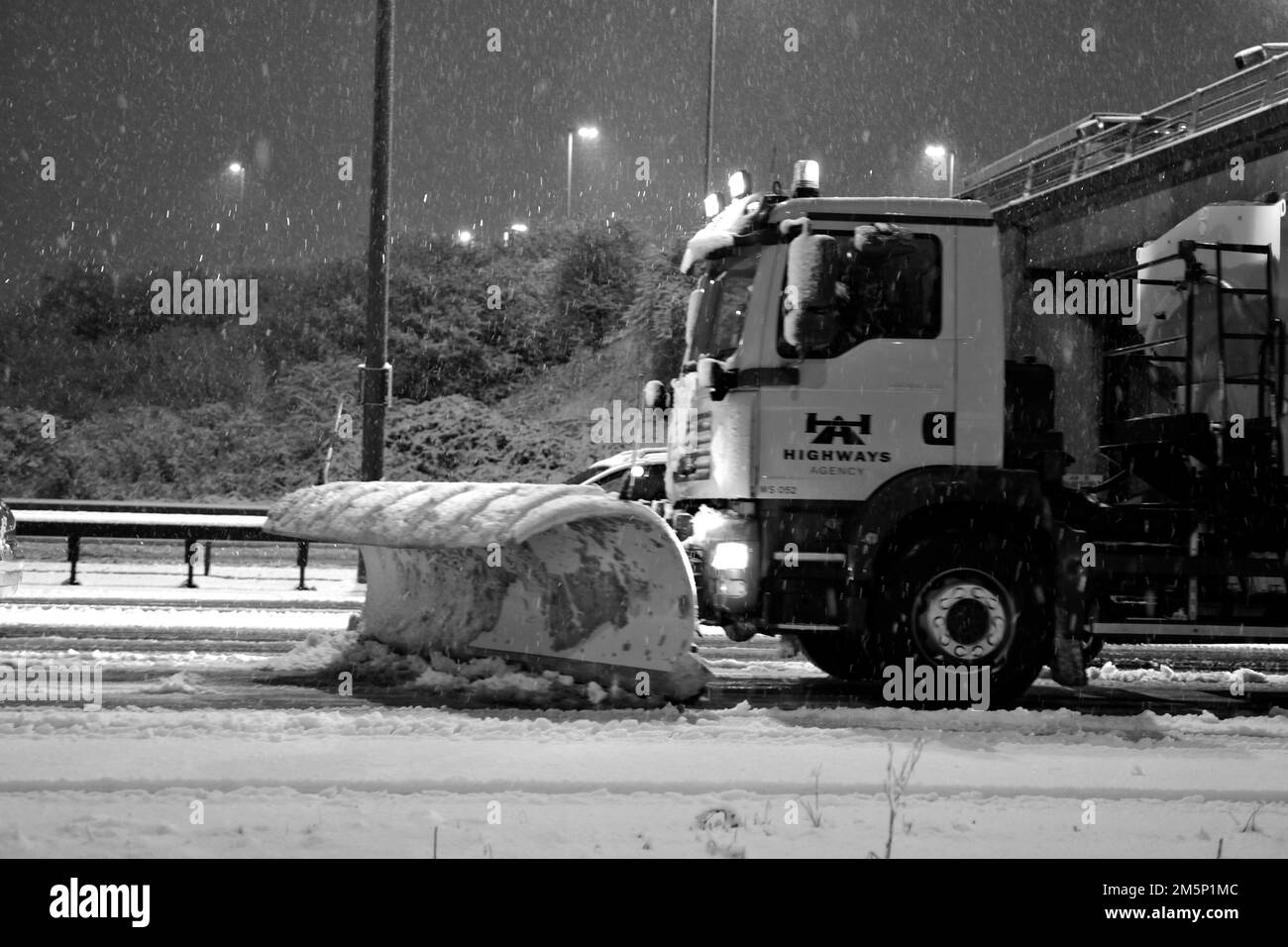 Neve pesante che cade sul M27 di notte con i veicoli gritting che lottano per far fronte, M27, vicino a Portsmouth, Hampshire, Inghilterra, REGNO UNITO Foto Stock