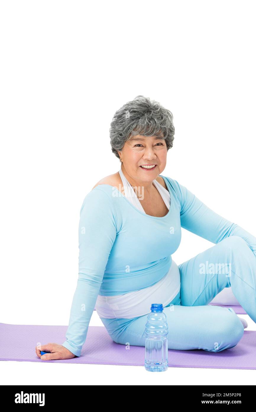 La vecchia donna sedette nel tappetino yoga Foto Stock
