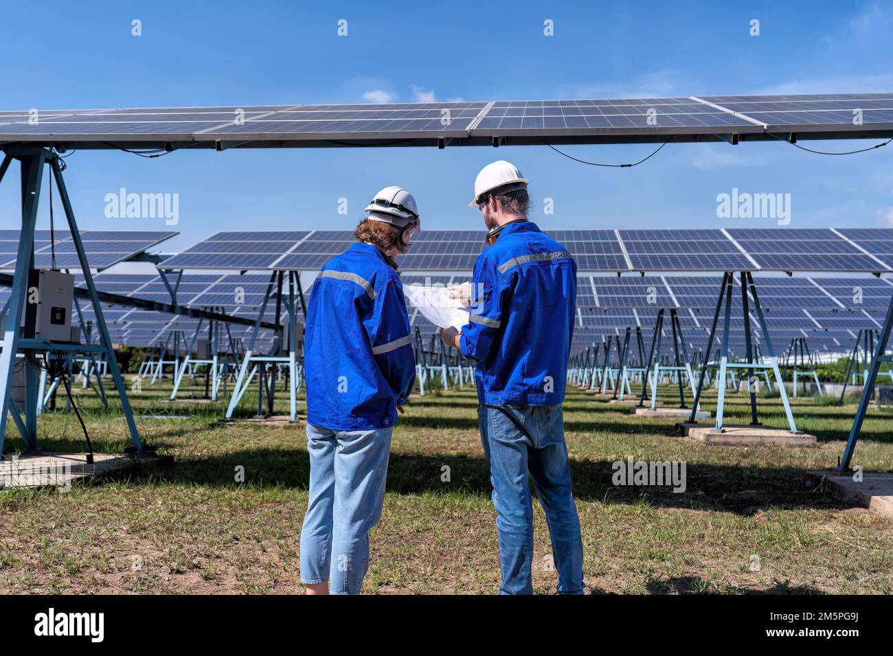 Ingegnere di manutenzione presso la fattoria solare guardare disegno discutere su espansione aggiornamento impianto elettrico Foto Stock