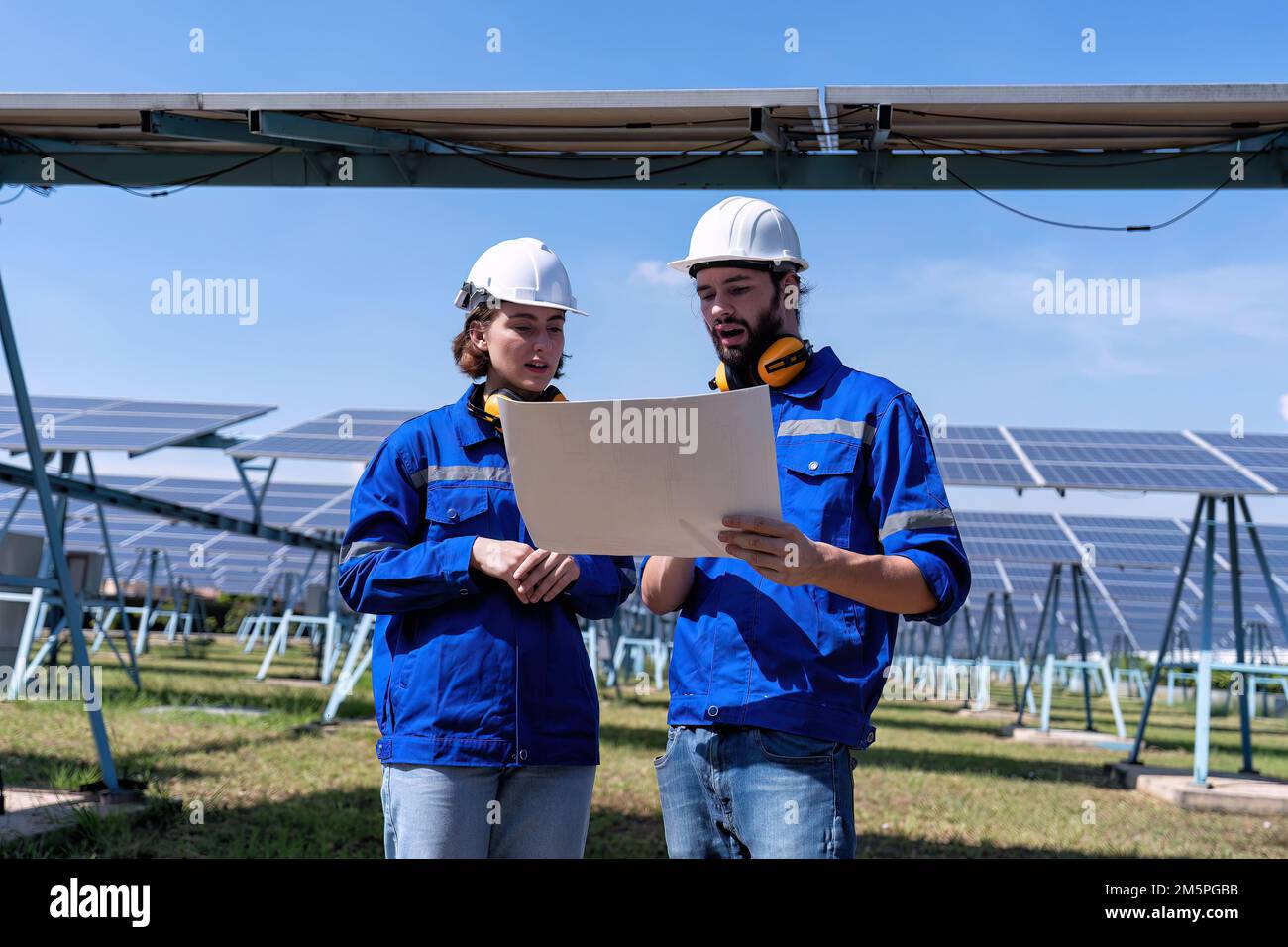 Ingegnere di manutenzione presso la fattoria solare guardare disegno discutere su espansione aggiornamento impianto elettrico Foto Stock