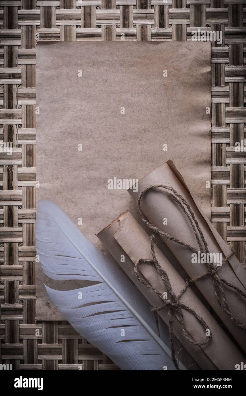 Foglio bianco medievale di carta arrotolata su sfondo di legno di vimini. Foto Stock