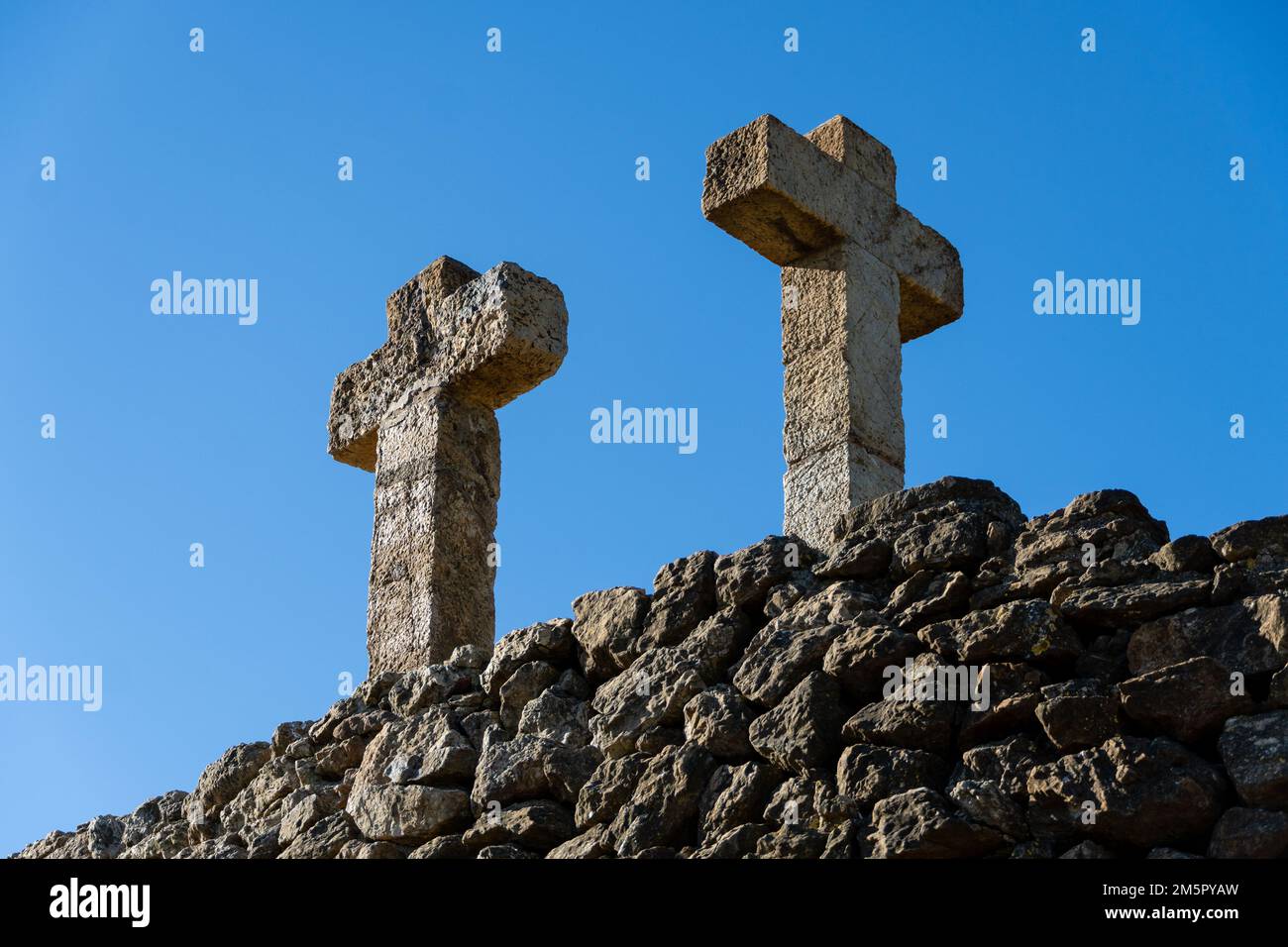 Vecchia croce di pietra e vecchio muro di pietra di mattoni con cielo blu - sfondo religioso Foto Stock