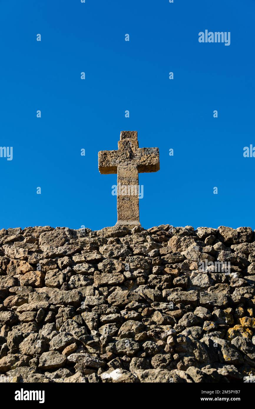 Vecchia croce di pietra e vecchio muro di pietra di mattoni con cielo blu - sfondo religioso Foto Stock