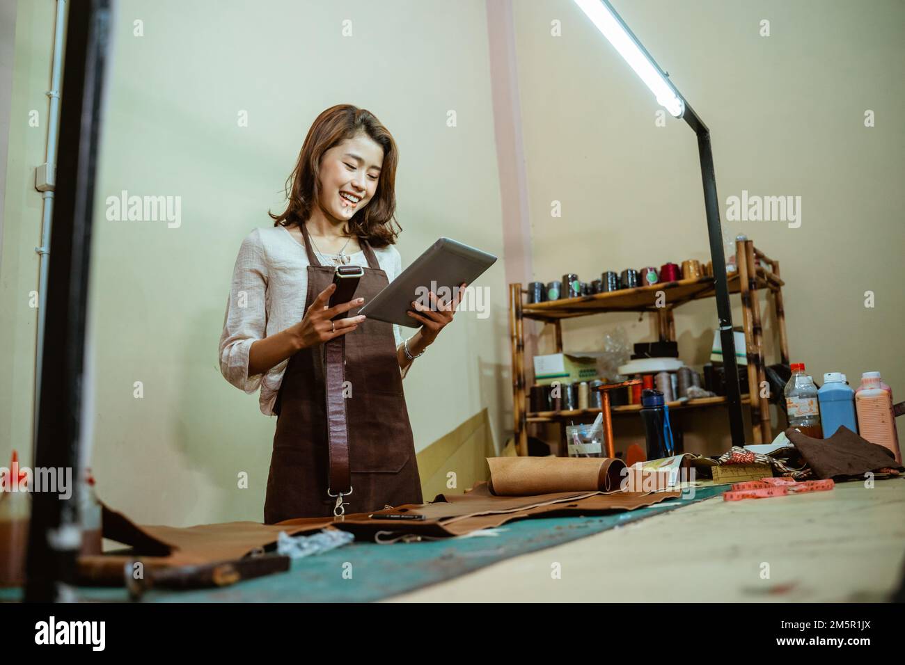 Gli artigiani asiatici usano i tablet digitali per trovare i riferimenti Foto Stock