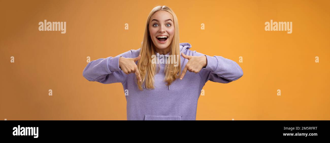 Emozionato europeo carino ragazza bionda capelli sorridenti aperti bocca divertente dire guardare verso il basso verso il basso incredibile fresco nuovo prodotto Foto Stock