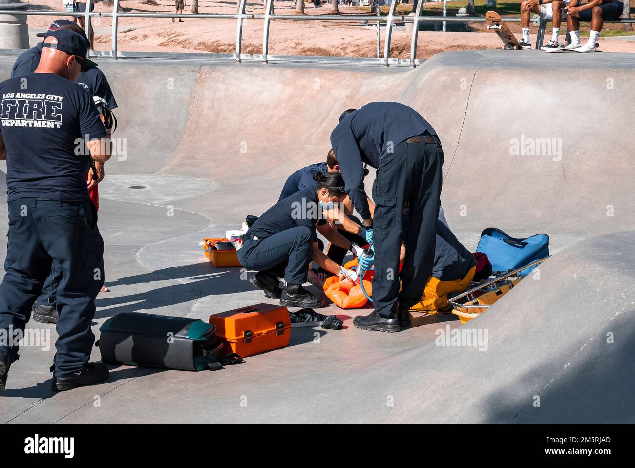 Squadra di soccorso che dà trattamento all'uomo ferito sulla rampa di skateboard al parco Foto Stock