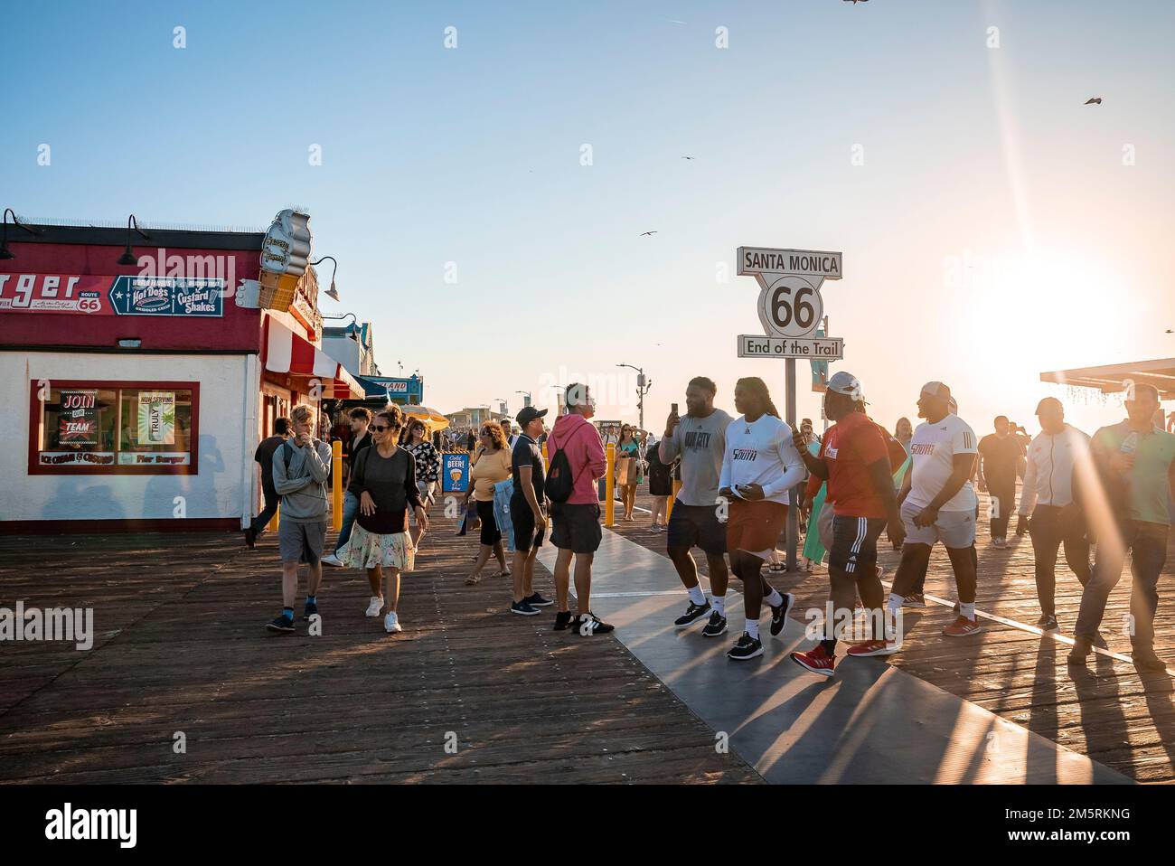 Persone che camminano a Santa Monica 66 fine del cartello del sentiero sul molo al tramonto Foto Stock