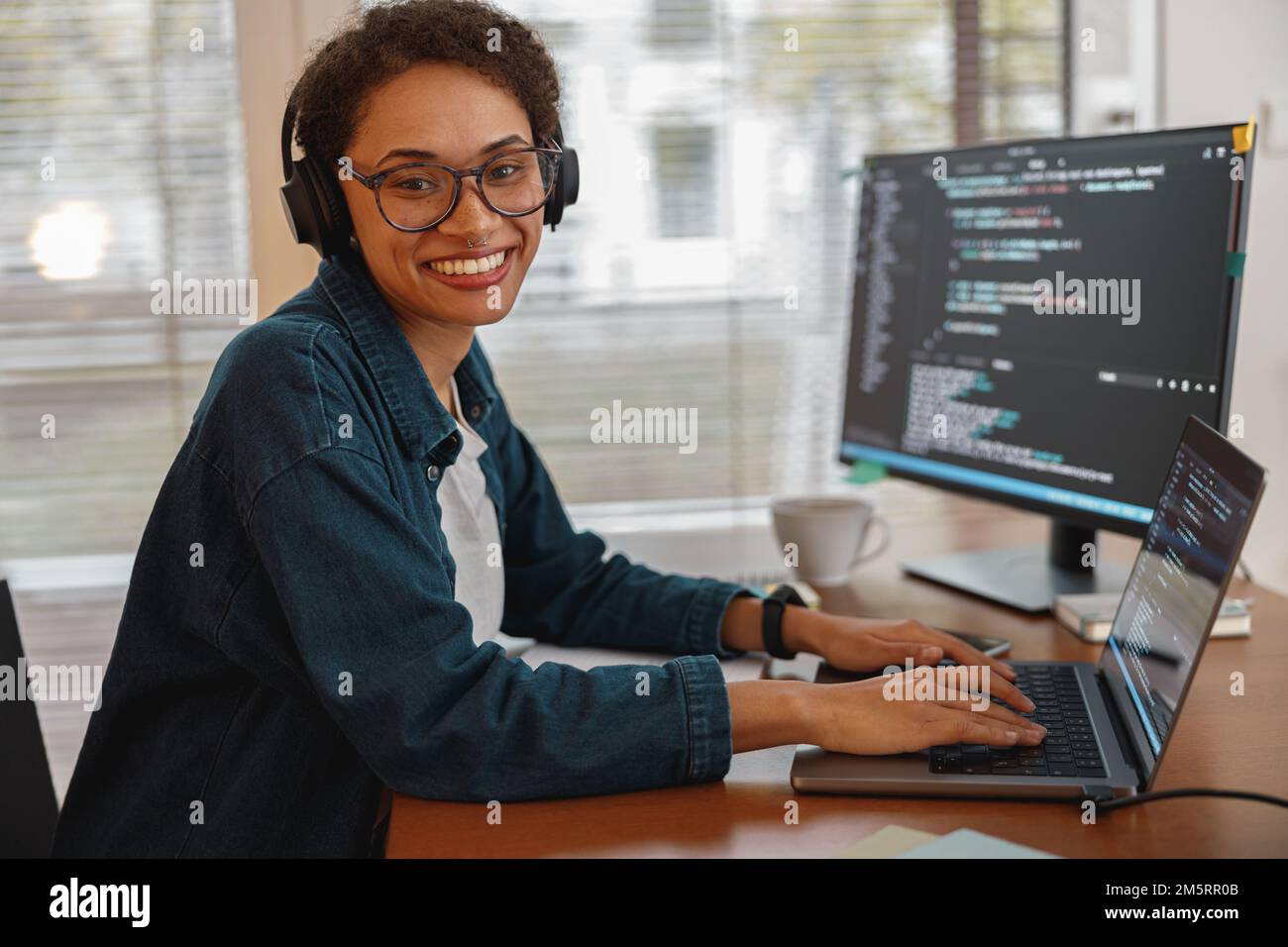 Donna afro-americana in cuffie scienziato freelance dati lavoro a distanza in casa ufficio Foto Stock