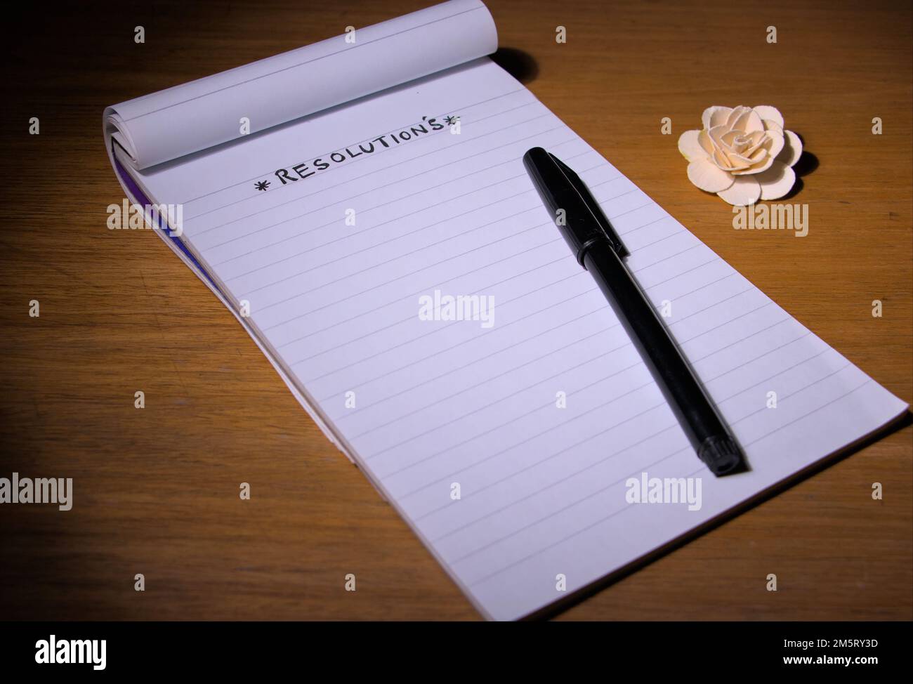 RISOLUZIONE scritta su un blocco note o un libro con una penna sul tavolo. Foto Stock