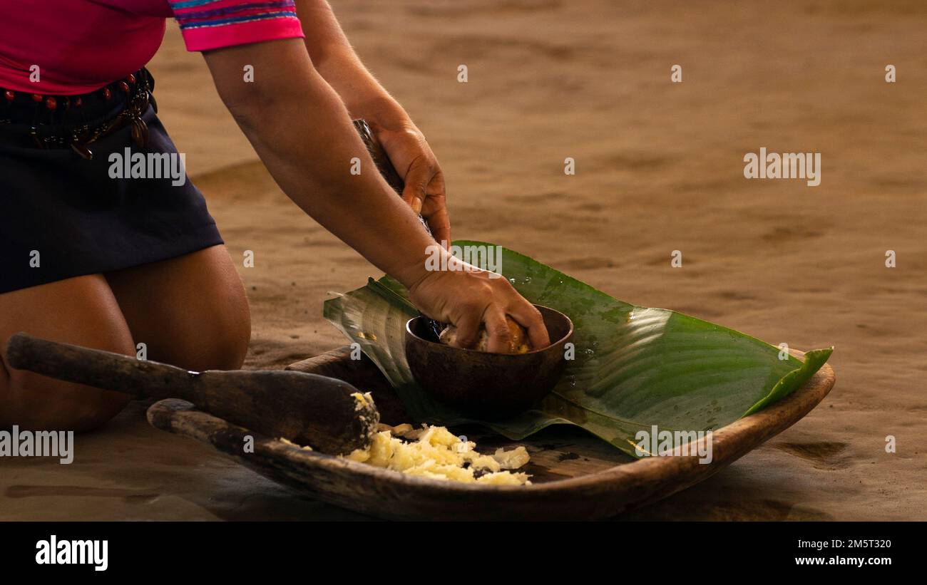 Dimostrazione di una donna indigena che fa il chicha tradizionale con manioca in Amazzonia Foto Stock