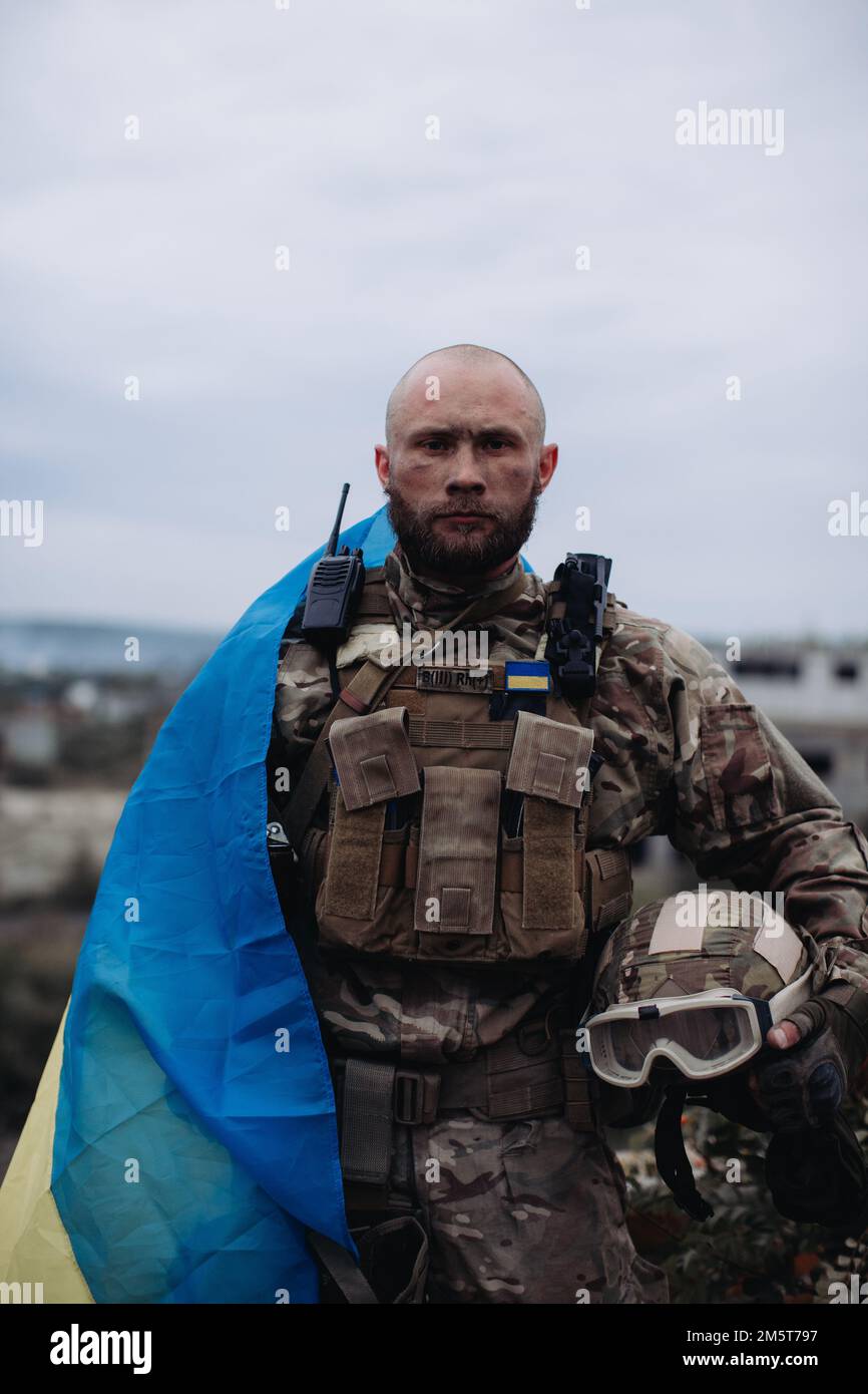 Un uomo militare detiene la bandiera dell'Ucraina. Ritratto del difensore dell'Ucraina. Foto Stock