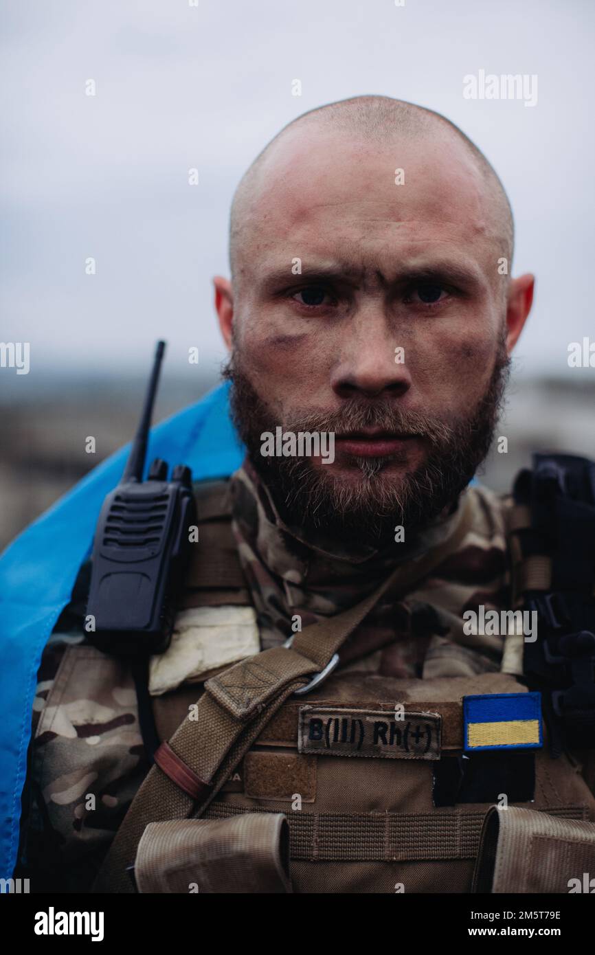 Un uomo militare detiene la bandiera dell'Ucraina. Ritratto del difensore dell'Ucraina. Foto Stock