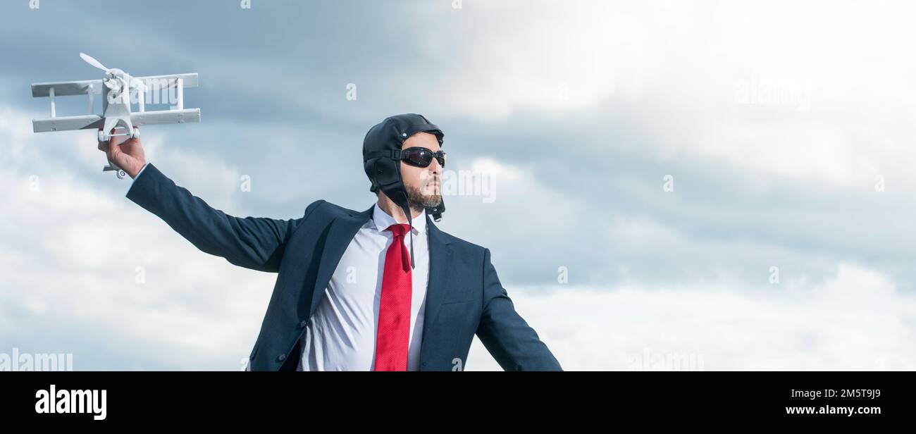 uomo d'affari in tuta e cappello pilota lancio aereo giocattolo su sfondo cielo. spazio di copia Foto Stock