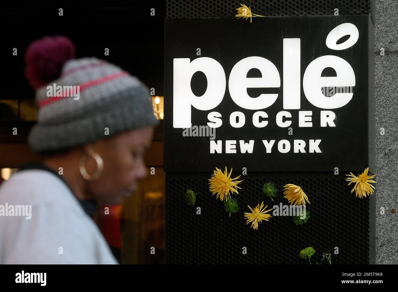 New York, Stati Uniti. 30th Dec, 2022. Una donna passa accanto ai fiori posti sulla parte anteriore del negozio di Pele Soccer a Times Square, dopo la notizia del leggendario giocatore brasiliano morto il giorno precedente, New York, NY, 30 dicembre 2022. Conosciuto come Pele, Edson Arantes do Nascimento è morto a 82 anni dal cancro il 29 dicembre, ed è considerato come un'icona dello sport del calcio. (Foto di Anthony Behar/Sipa USA) Credit: Sipa USA/Alamy Live News Foto Stock