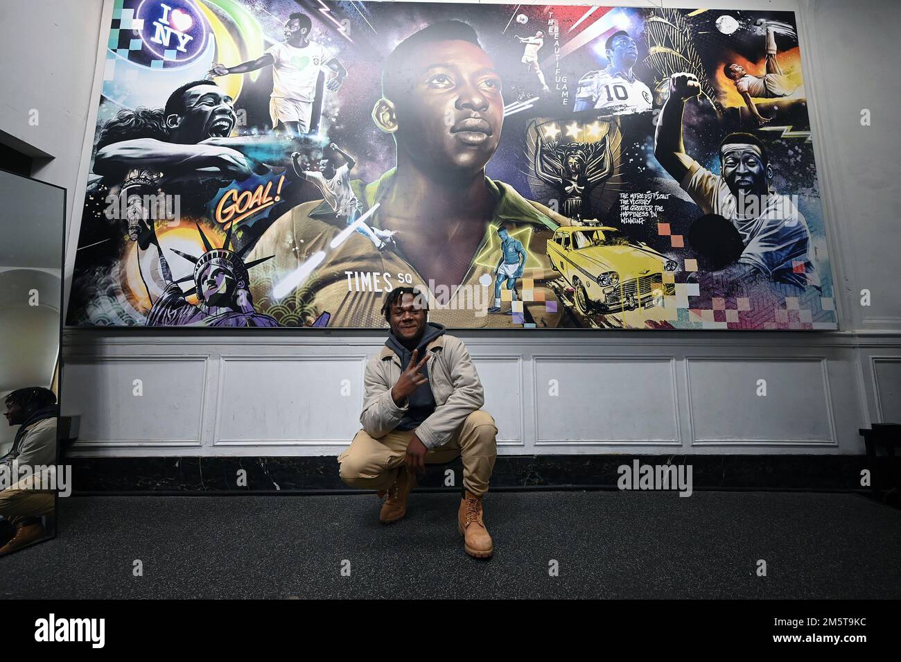 New York, Stati Uniti. 30th Dec, 2022. Jerimiah Bimah, in visita dal Minnesota, si pone di fronte a un murale dedicato al giocatore brasiliano di calcio Pele, all'interno del negozio di Pele Soccer a Times Square, New York, NY, 30 dicembre 2022. Conosciuto come Pele, Edson Arantes do Nascimento è morto a 82 anni dal cancro il 29 dicembre, ed è considerato come un'icona dello sport del calcio. (Foto di Anthony Behar/Sipa USA) Credit: Sipa USA/Alamy Live News Foto Stock