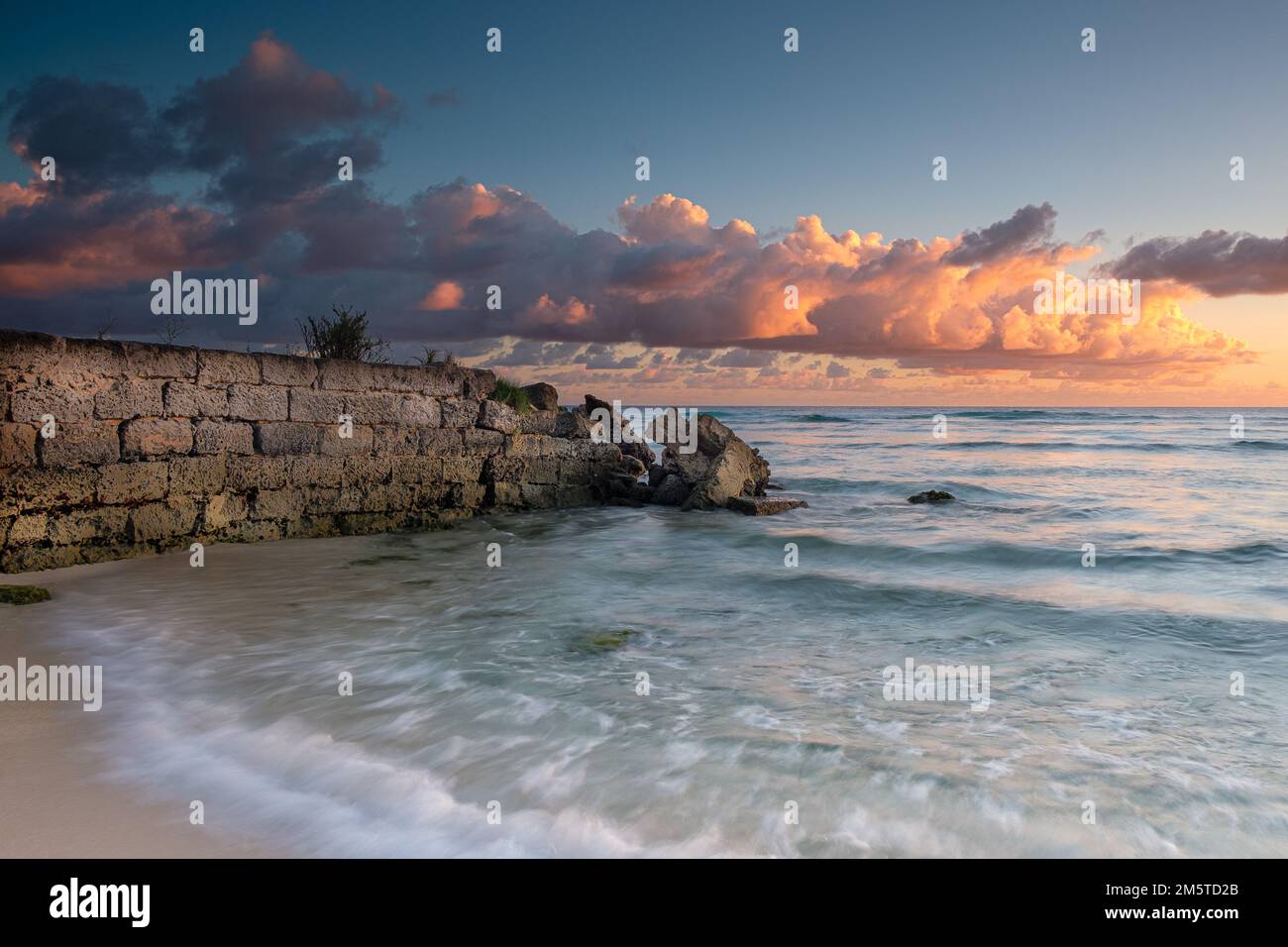 Tramonto alle Barbados - nuvole rosa e muro di pietra Foto Stock