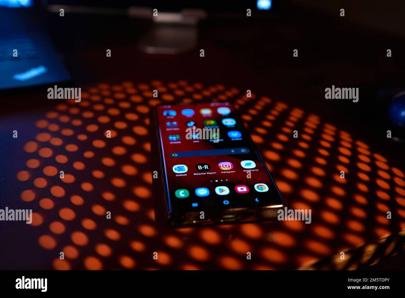 Telefono cellulare con applicazioni luminose visualizzate sull'ombra del tavolo Foto Stock