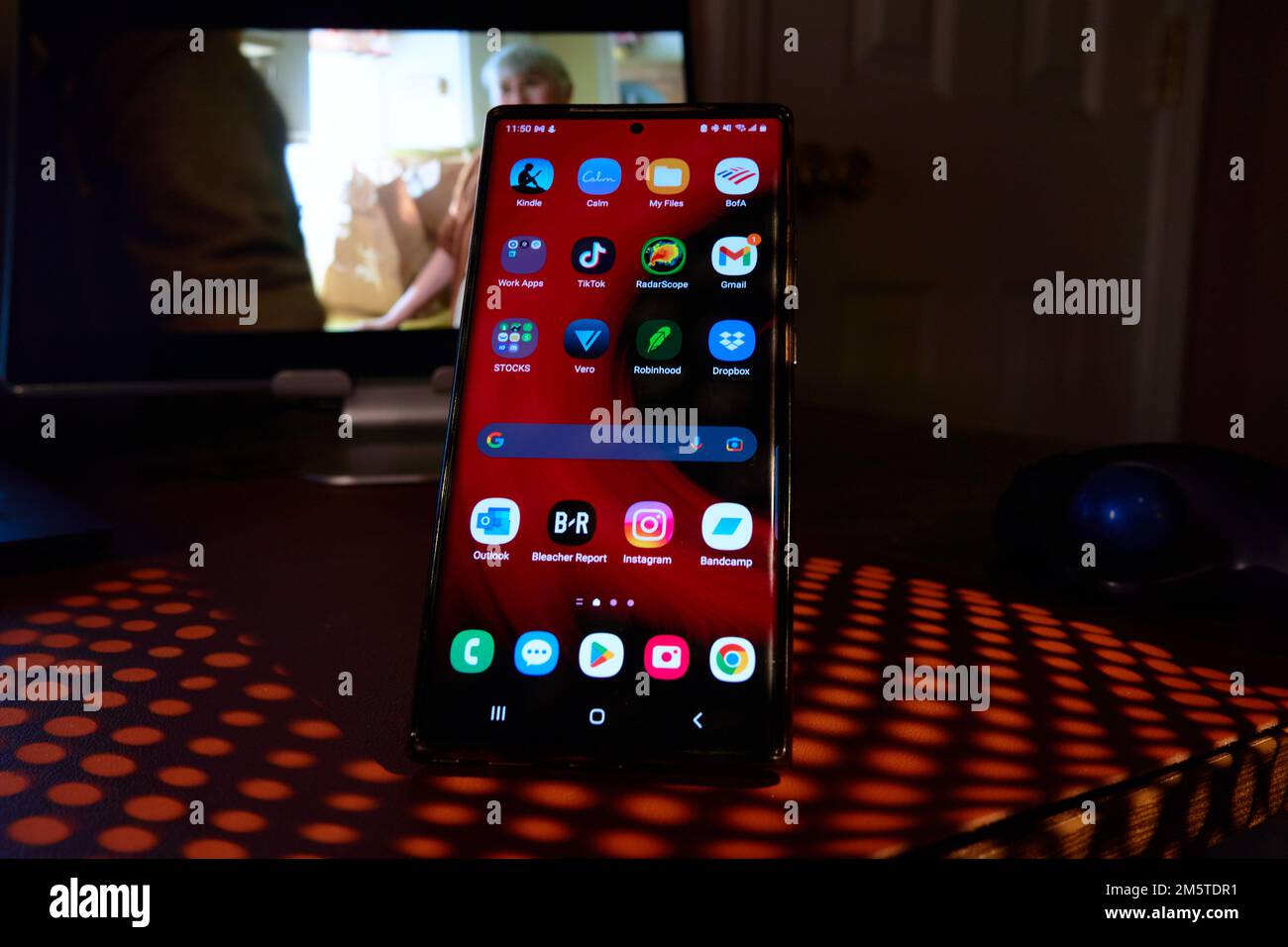 Telefono cellulare con applicazioni luminose visualizzate sull'ombra del tavolo Foto Stock