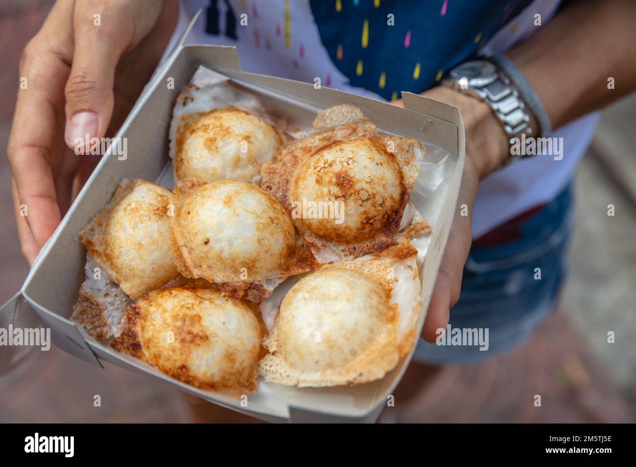 Una scatola di Khanom khrok o frittelle al cocco-riso, dessert tradizionale tailandese con latte di cocco e fiore di riso. Cucina nazionale della Thailandia. Foto Stock