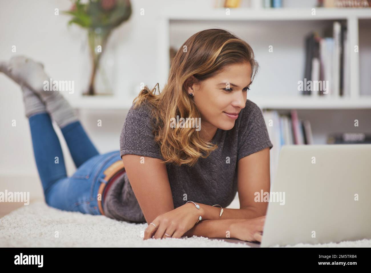 Aggiornamento dello stato Lazy weekend a casa. una giovane donna che si rilassa a casa con il suo notebook. Foto Stock