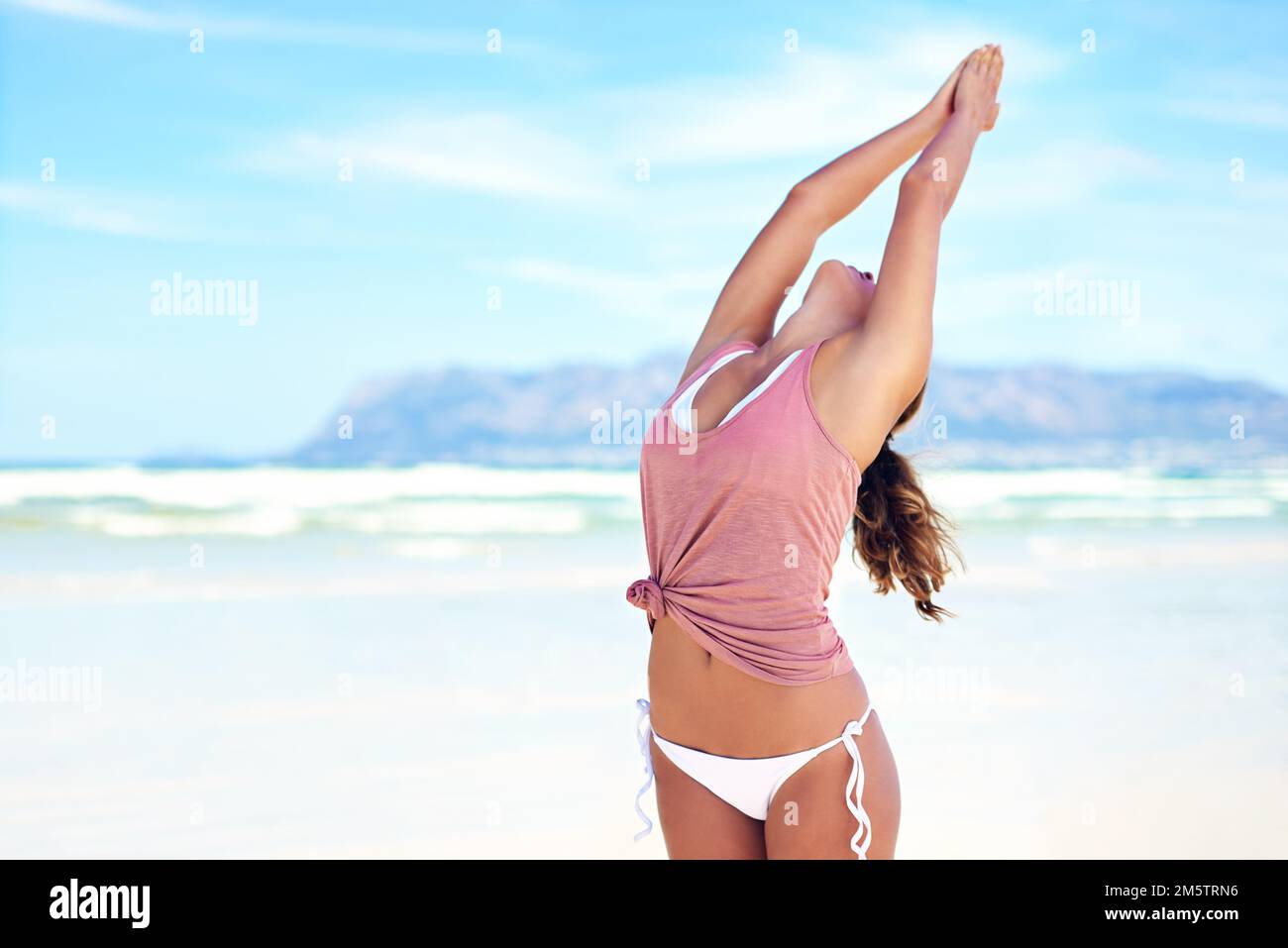 Allunga la mente. una giovane donna che fa yoga in spiaggia. Foto Stock