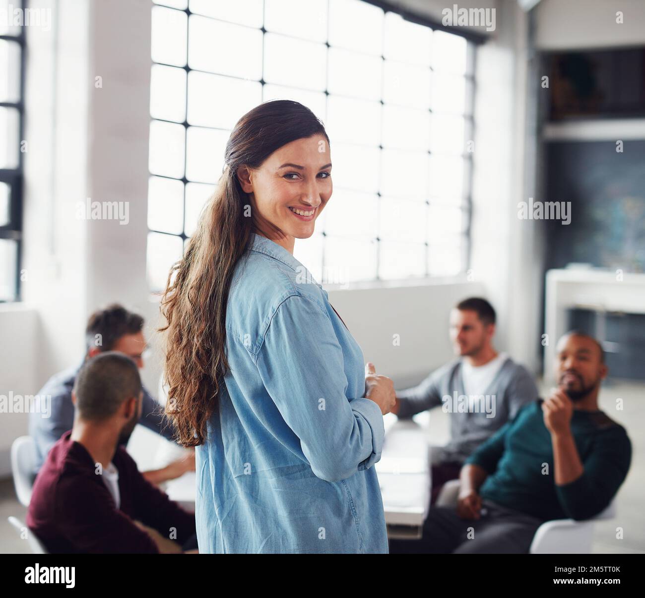 La mia squadra ha questo. Ritratto di una donna sorridente che guarda sopra la spalla mentre fa una presentazione ai colleghi in un ufficio. Foto Stock