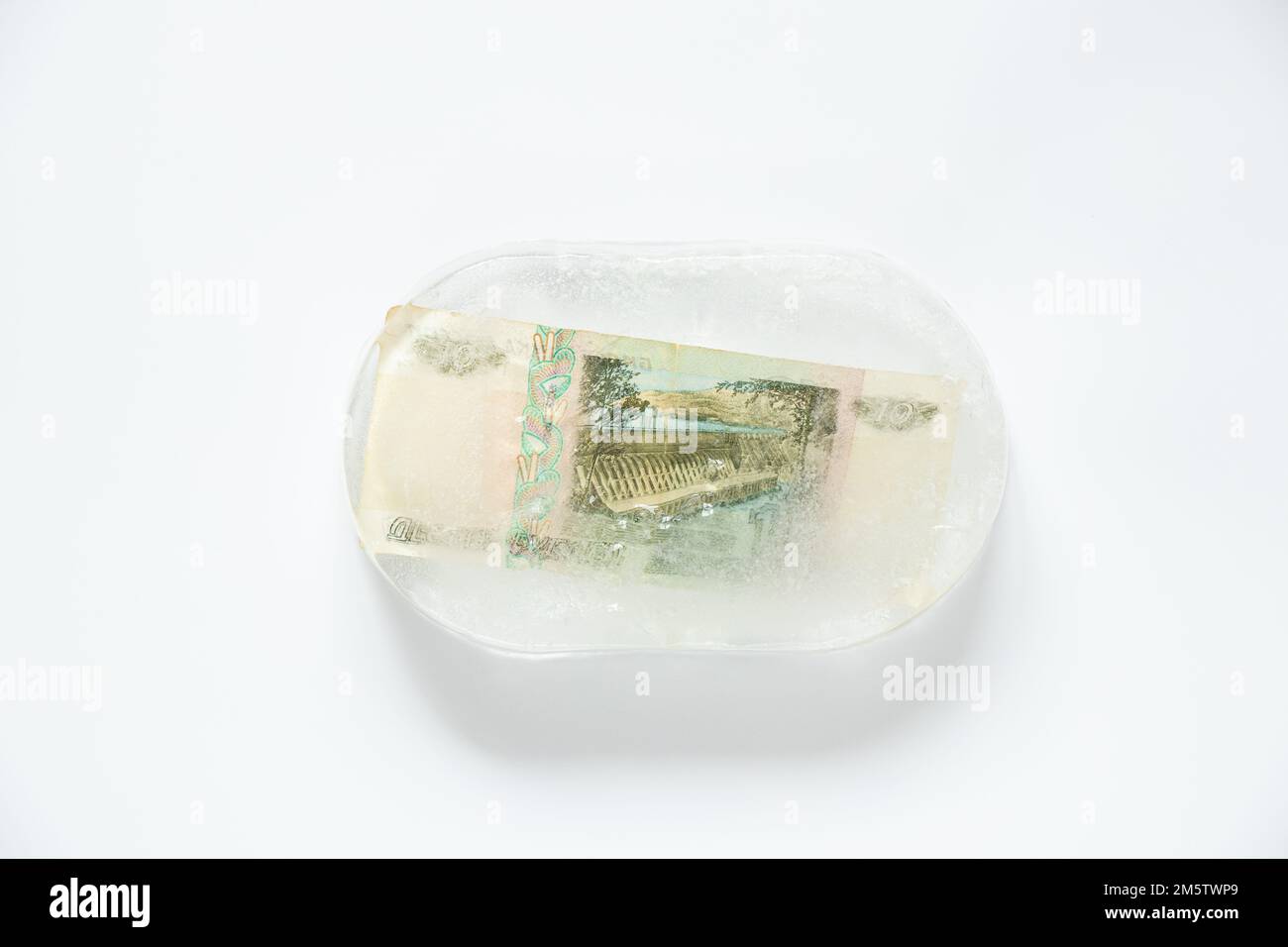 Dieci rubli congelati in un pezzo di ghiaccio su uno sfondo bianco, finanza ed economia russa, crisi rublo, default Foto Stock