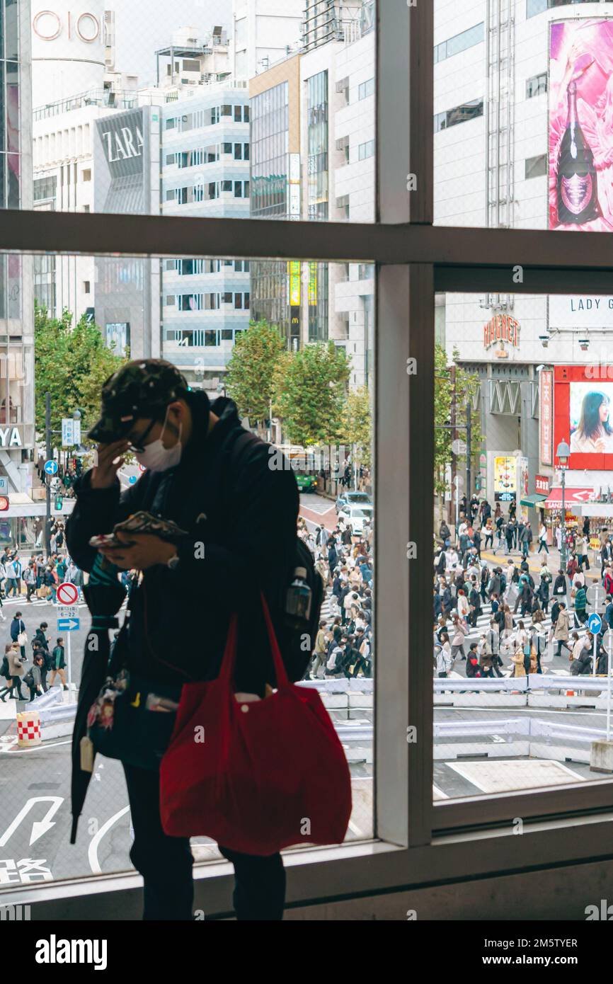 Un giovane che guarda stressato con Shibuya attraversamento sullo sfondo Foto Stock