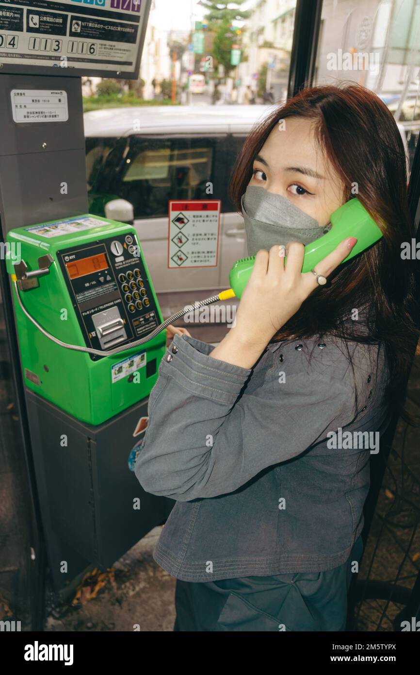 Giovane ragazza che effettua una chiamata telefonica alla cabina del telefono Foto Stock