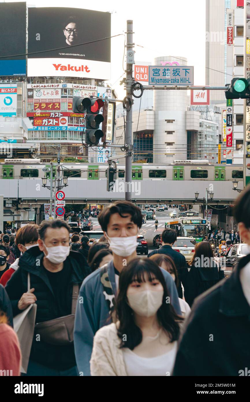 Folle di persone in maschera sulle strade trafficate del centro città di Shibuya Foto Stock