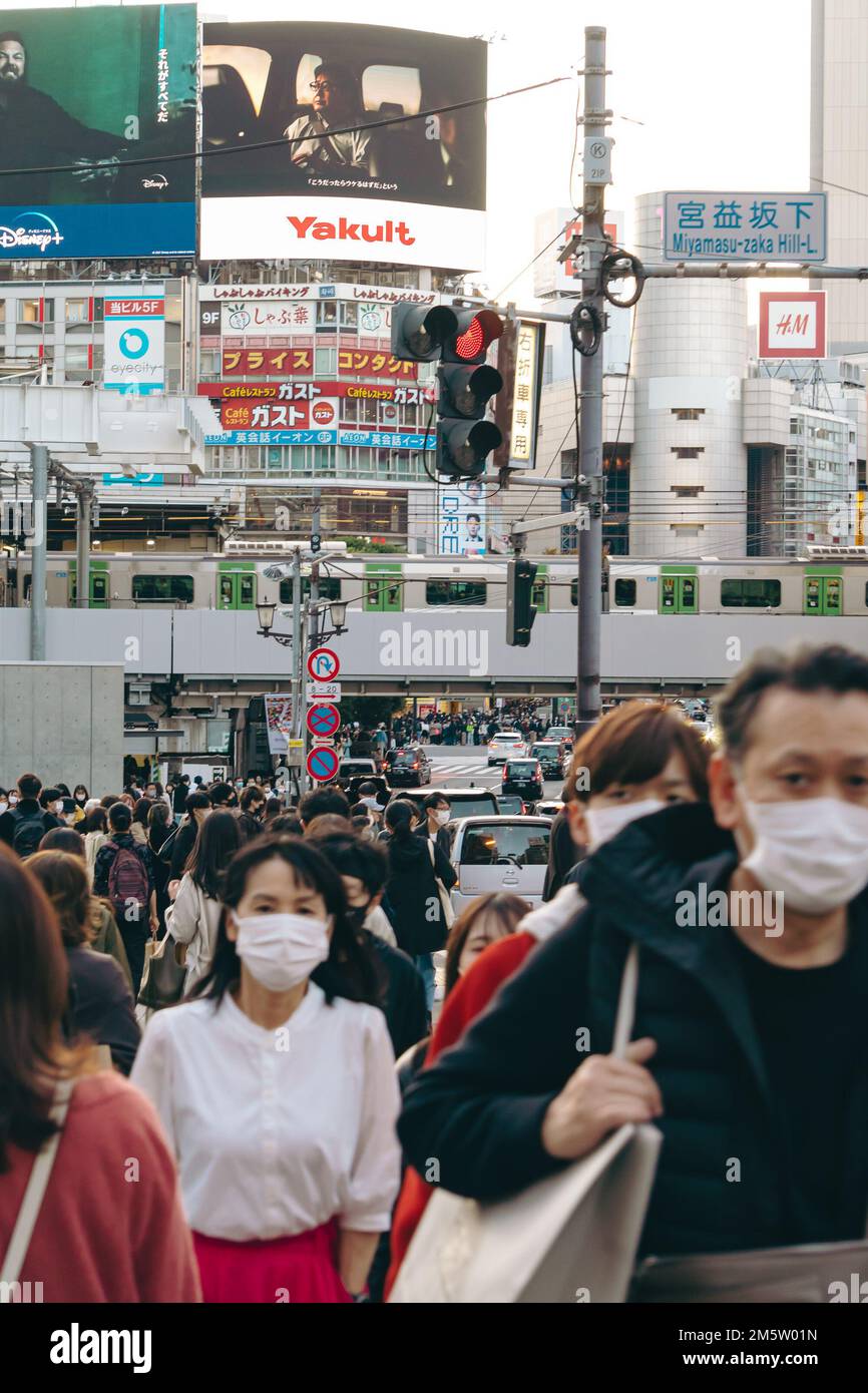 Folle di persone in maschera sulle strade trafficate del centro città di Shibuya Foto Stock