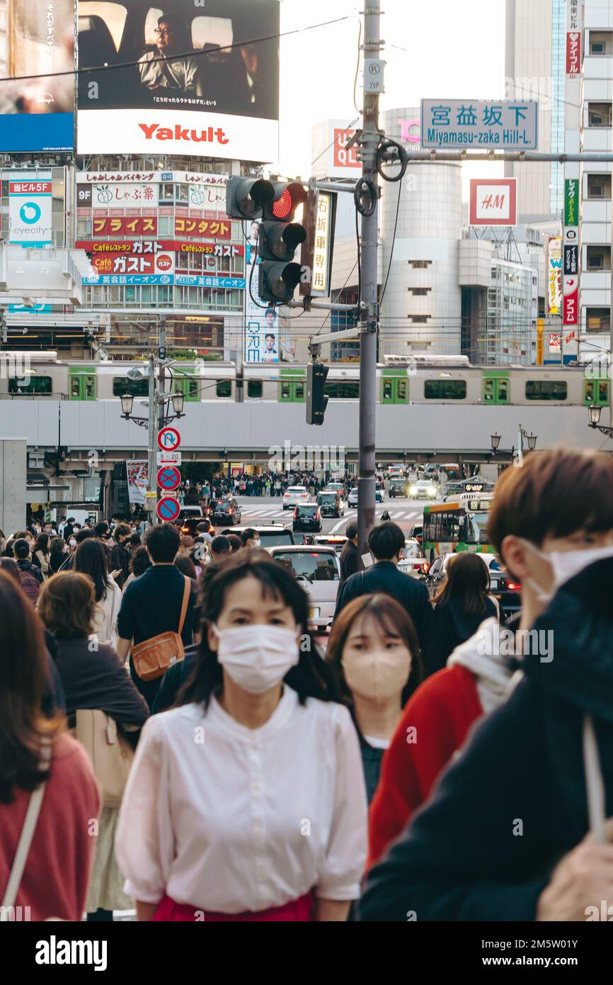 Folle di persone in maschera sulle strade trafficate del centro città di Shibuya Foto Stock