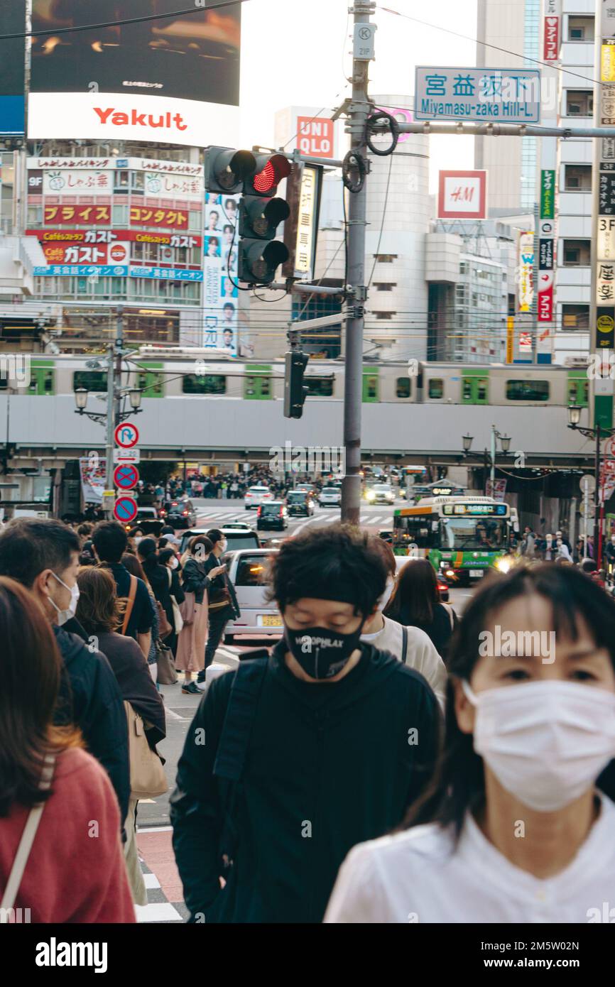 Folle di persone in maschera sulle strade trafficate del centro città di Shibuya Foto Stock