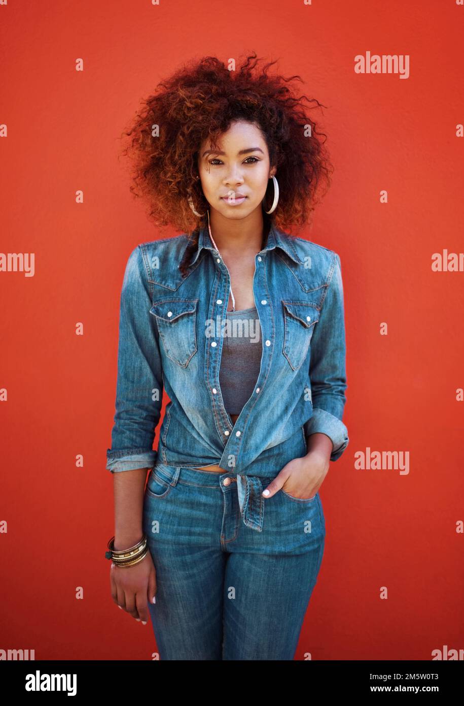 Bella e lei lo sa. Ritratto di una giovane donna attraente che si posa su uno sfondo rosso. Foto Stock