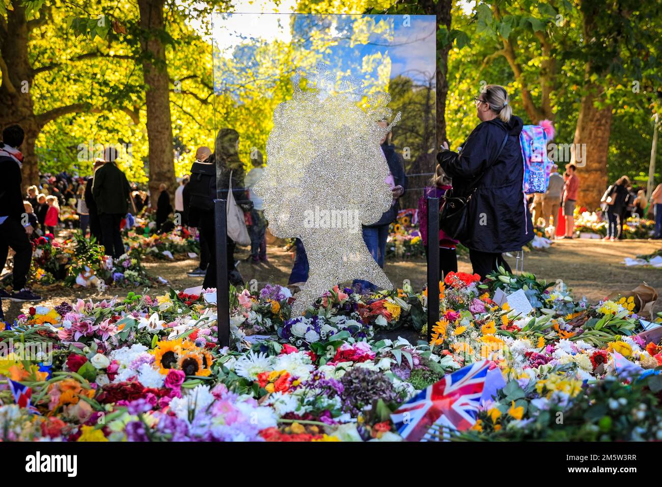Una silhouette di vetro e tributi floreali con i lutto visitano Green Park dopo la morte della Regina Elisabetta II, Londra, Regno Unito Foto Stock