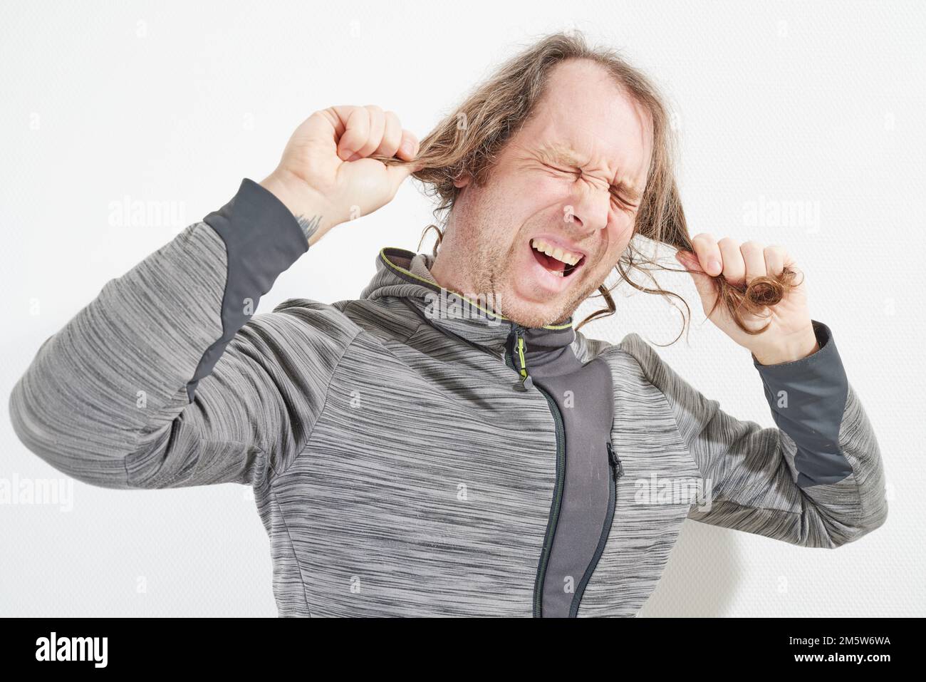 L'uomo arrabbiato per i suoi lunghi capelli Foto Stock