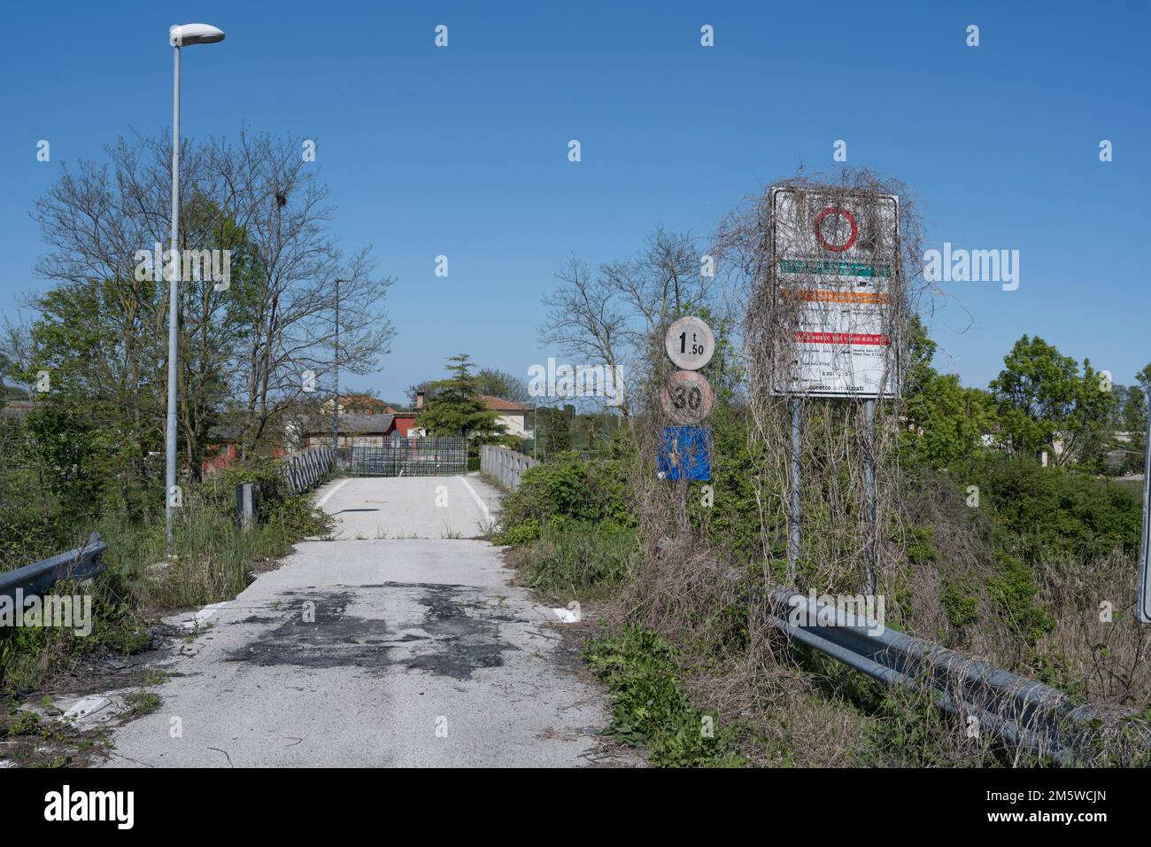 I cartelli stradali sono cresciuti con piante di fronte ad un ponte chiuso, Venezia, Italia Foto Stock
