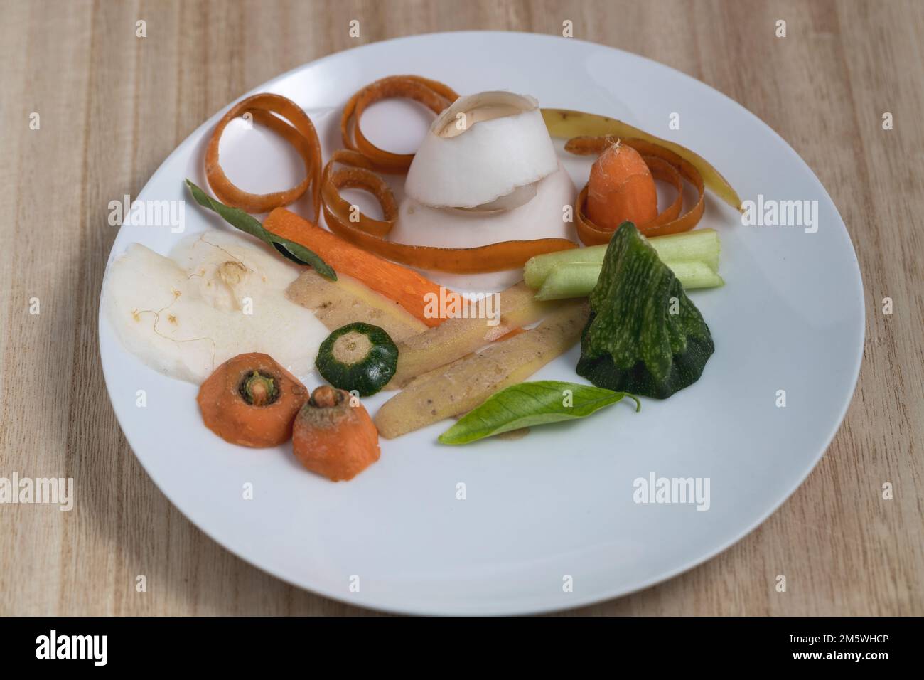 Grattugiare e sbucciare le verdure su un piatto bianco. Rifiuti di cucina, sostenibilità alimentare, compost. Foto Stock