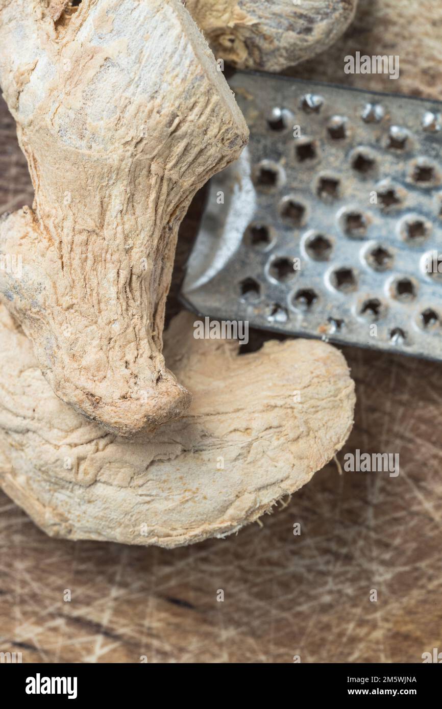 Ingrediente sano: Zenzero essiccato su legno con grattugia. Spezie per cucinare o tè. Foto Stock