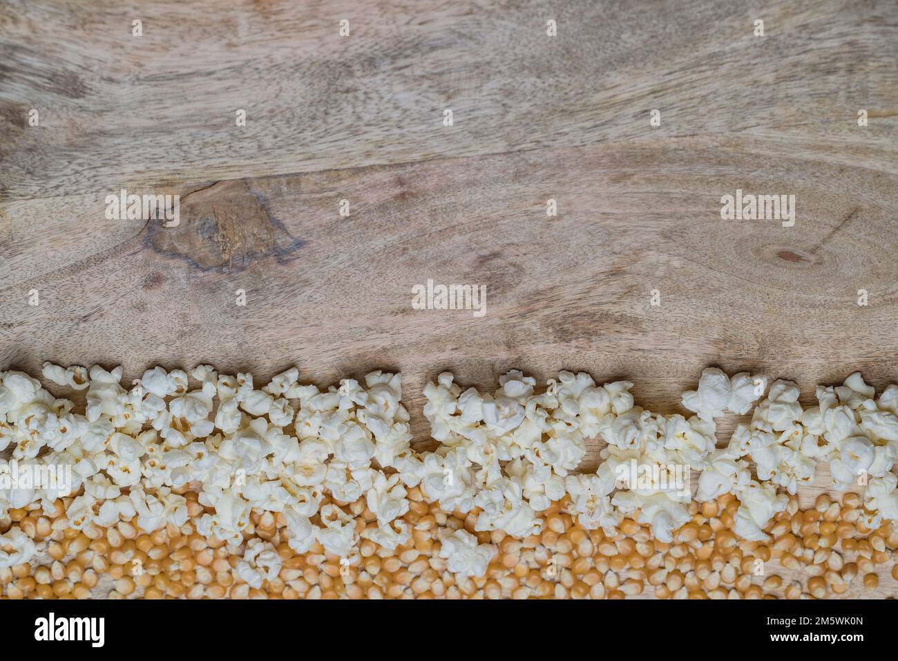Bordo di popcorn e chicchi su una superficie rustica in legno. Ingredienti per spuntini. Foto Stock